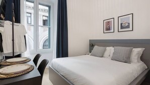 A modern hotel room with a large bed, a dining table with placemats, and two framed pictures on the wall. - Cozy Trieste Historic Hideaway (Trieste)