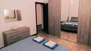 Quarto moderno com cama, mesas de cabeceira, espelho e guarda-roupa.