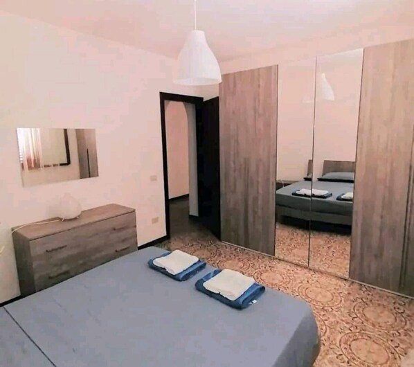 Une chambre à coucher moderne avec un lit, des tables de chevet, un miroir et une armoire.