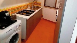 Cozinha compacta com máquina de lavar, fogão e pia.