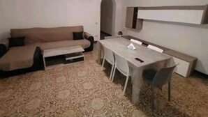 Uma sala de estar com sofá, mesa de centro e mesa de jantar com cadeiras.