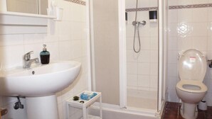 A bathroom with a white sink, a mirror, a shower enclosure, and a toilet.