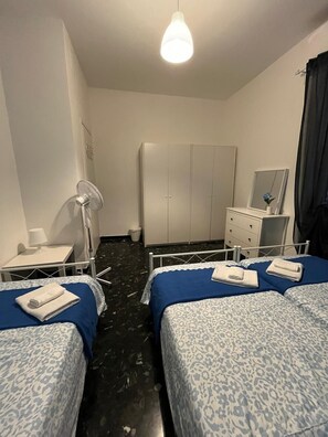 Een hotelkamer met twee bedden, een nachtkastje met een lamp, een kledingkast en een spiegel aan de muur.