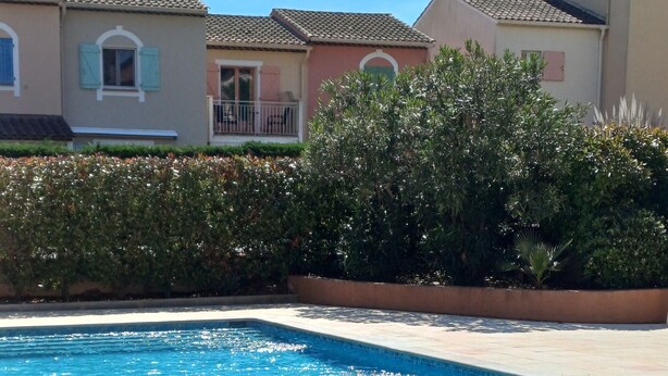 Una piscina rectangular con agua azul cristalina, rodeada por un solárium con baldosas.