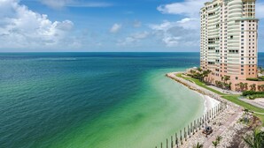 A high-rise hotel with a beachfront view, a sandy beach, and a clear blue ocean. - Elevated Elegance With Gulf Scanning Panorama (Marco Island)