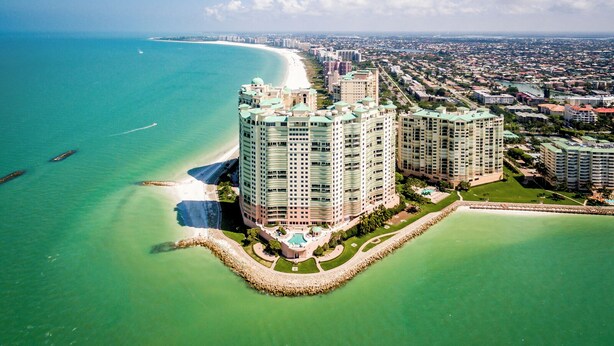 A high-rise hotel with a curved design, located near a beach and ocean, featuring a pool and landscaped areas. - Elevated Elegance With Gulf Scanning Panorama (Marco Island)