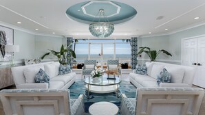 A spacious living room with a large glass coffee table, white sofas, and a view of the ocean through large windows. - Elevated Elegance With Gulf Scanning Panorama (Marco Island)
