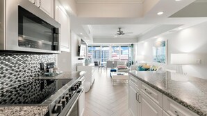 A modern kitchen with stainless steel appliances, a herringbone tile backsplash, and a view to the living area. - Monthly Executive Picturesque Sunset Retreat (Marco Island)
