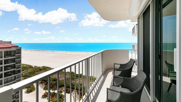 A balcony with wicker furniture overlooking a beach and ocean. - Monthly Executive Picturesque Sunset Retreat (Marco Island)