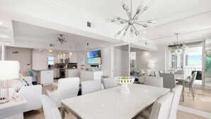 A modern kitchen with a large island, white cabinetry, and a flat-screen TV. - Monthly Executive Picturesque Sunset Retreat (Marco Island)