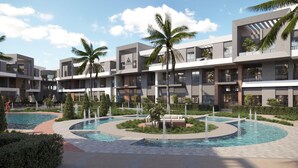Un hotel moderno con varias piscinas, palmeras y un jardín bien cuidado.