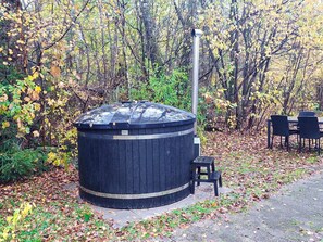 A hot tub in a wooded area with a table and chairs nearby. - 6 Person Holiday Home in Herning (Herning)