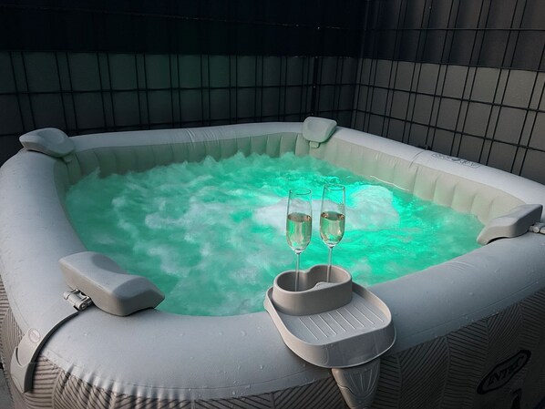 Ein aufblasbarer Whirlpool mit zwei Sektgläsern, einer Fußstütze und einer Bedieneinheit.