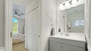 A bedroom with a bed, a closet, and a bathroom with a sink and mirror. - Island Oaks - your perfect Savannah escape! (Savannah)