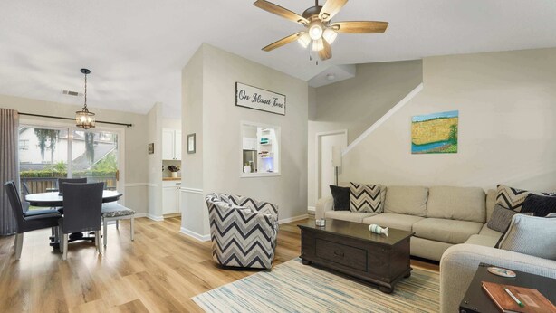A spacious living room with a dining area, a ceiling fan, a kitchen, and a staircase. - Island Oaks - your perfect Savannah escape! (Savannah)