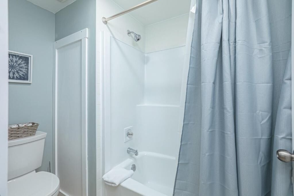 A bathroom with a shower, toilet, and a towel rack.