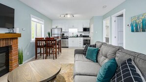 A modern living room with a fireplace, dining area, and kitchen. - The Alpine - Central Collingwood Condo (Collingwood)