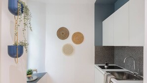 A modern kitchen with white cabinets, a granite countertop, and a stainless steel sink. - Trieste Time Capsule (Trieste)