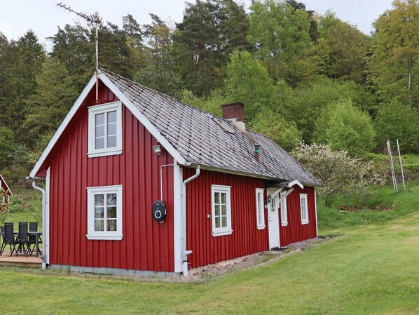 Ein rotes Holzhaus mit geneigtem Dach, weißem Zierdekor und einem Schornstein.