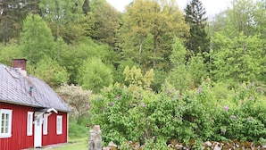 Ein rotes Holzhaus mit einer Steinmauer und einer steinernen Säule davor.