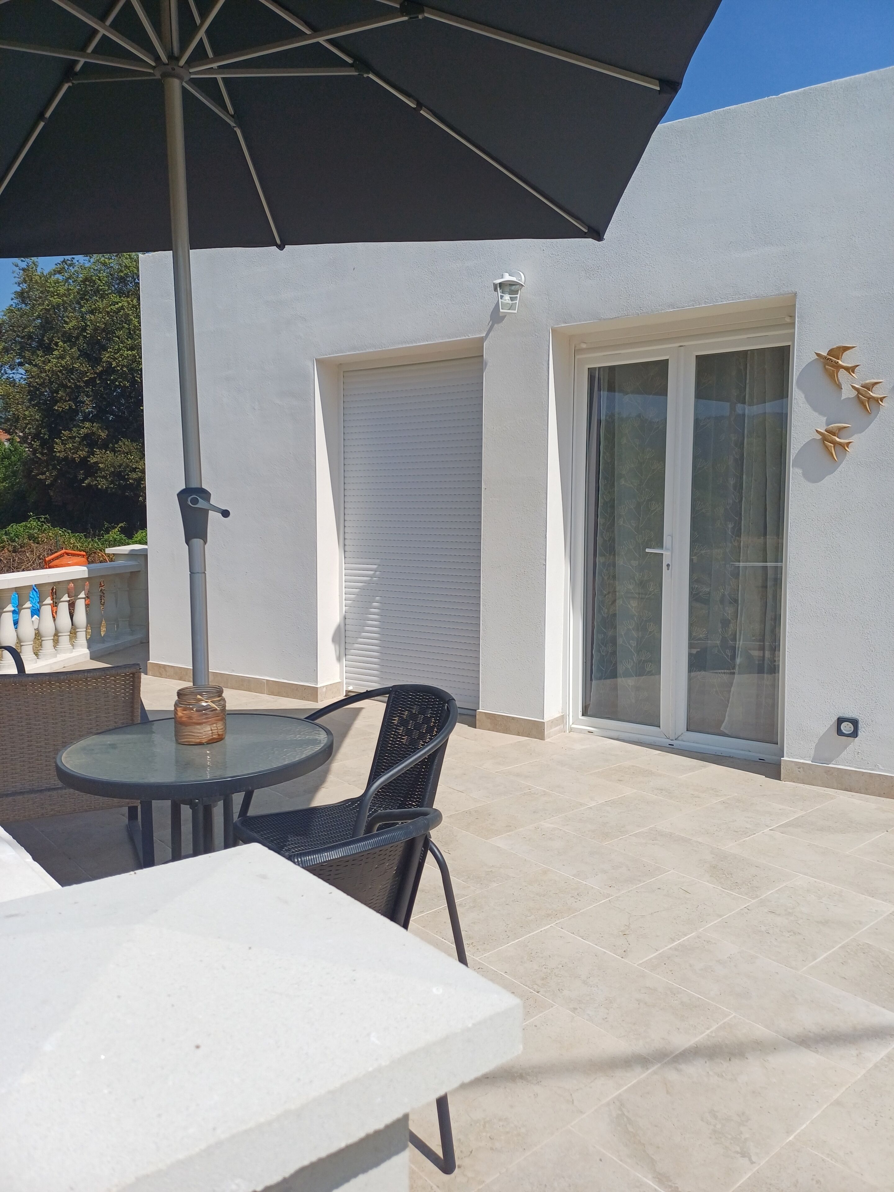 A patio with a round table, a chair, and a large umbrella.