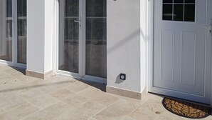 A building with a white exterior, a door with an arched window, and a set of sliding glass doors. - New, fully-equipped F2 gite in secure grounds (Hérépian)