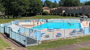 A swimming pool surrounded by a blue fence, with people swimming and lounging. - House 6 persons.2 bedrooms, 1 living room (Monflanquin)