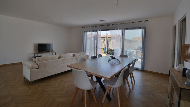 A modern living room with a sofa, dining table, and chairs.