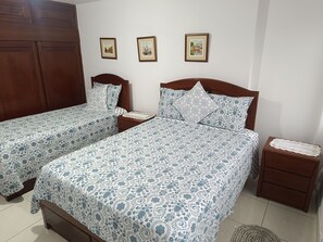 A bedroom with two single beds, wooden headboards, a nightstand, and a small bedside table with a decorative tray. - Charming 2-bedroom apartment in  San Miguel with WiFi and close to the airport (San Miguel)