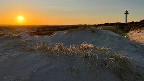Eine Küstenlandschaft mit Dünen und einem Leuchtturm.