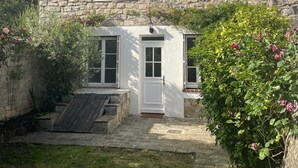 Una casa de piedra con un pequeño jardín delantero, una escalera de madera y una puerta.