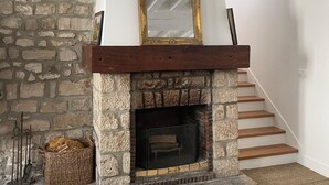 Una chimenea de piedra con una repisa de madera y un espejo encima.