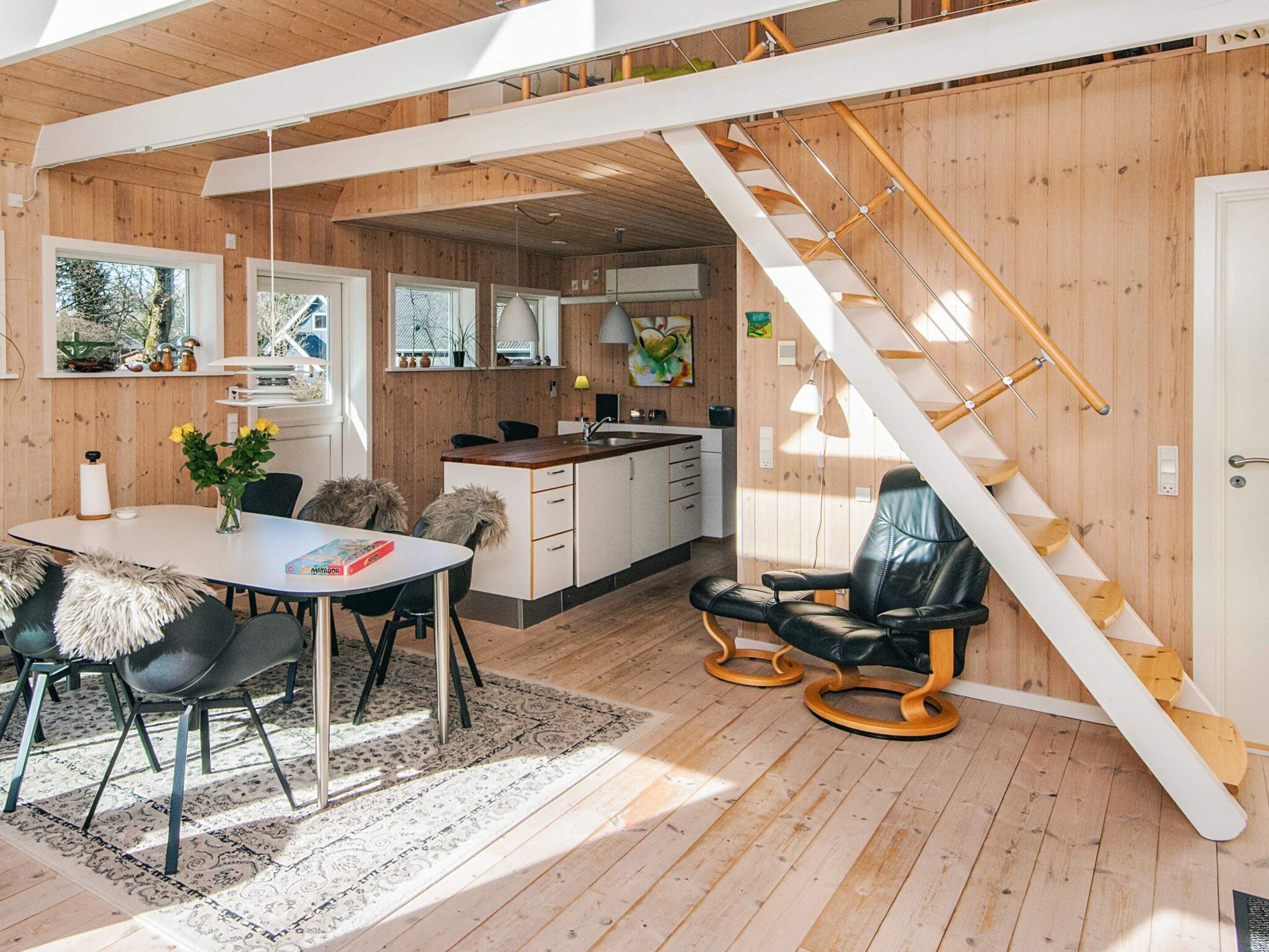 Un intérieur moderne comprenant un coin repas, une cuisine et un escalier.