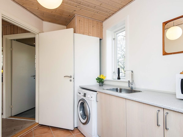 A compact kitchen with a washing machine, a sink, and a window.