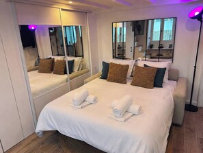 A hotel room with a large bed, two side mirrors, a bedside lamp, and a small seating area. - Cannes Croisette Festival Beach Sea (Cannes)