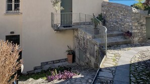 A Mediterranean-style building with a stone staircase, a balcony with a metal railing, and a view of mountains in the background. - Laglio Cesare’s House Lake View (Laglio)