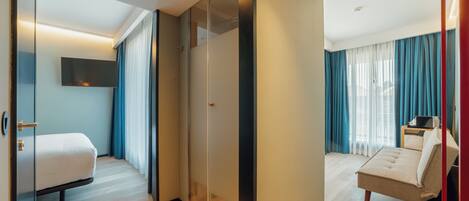 A hotel room with a bed, a seating area, a TV, and a sliding door.