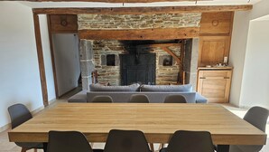 A dining area with a wooden table and chairs, a stone fireplace, and a cozy seating area. - Authentic Aubrac farmhouse with Jacuzzi. A change of scenery guaranteed! (Montpeyroux)
