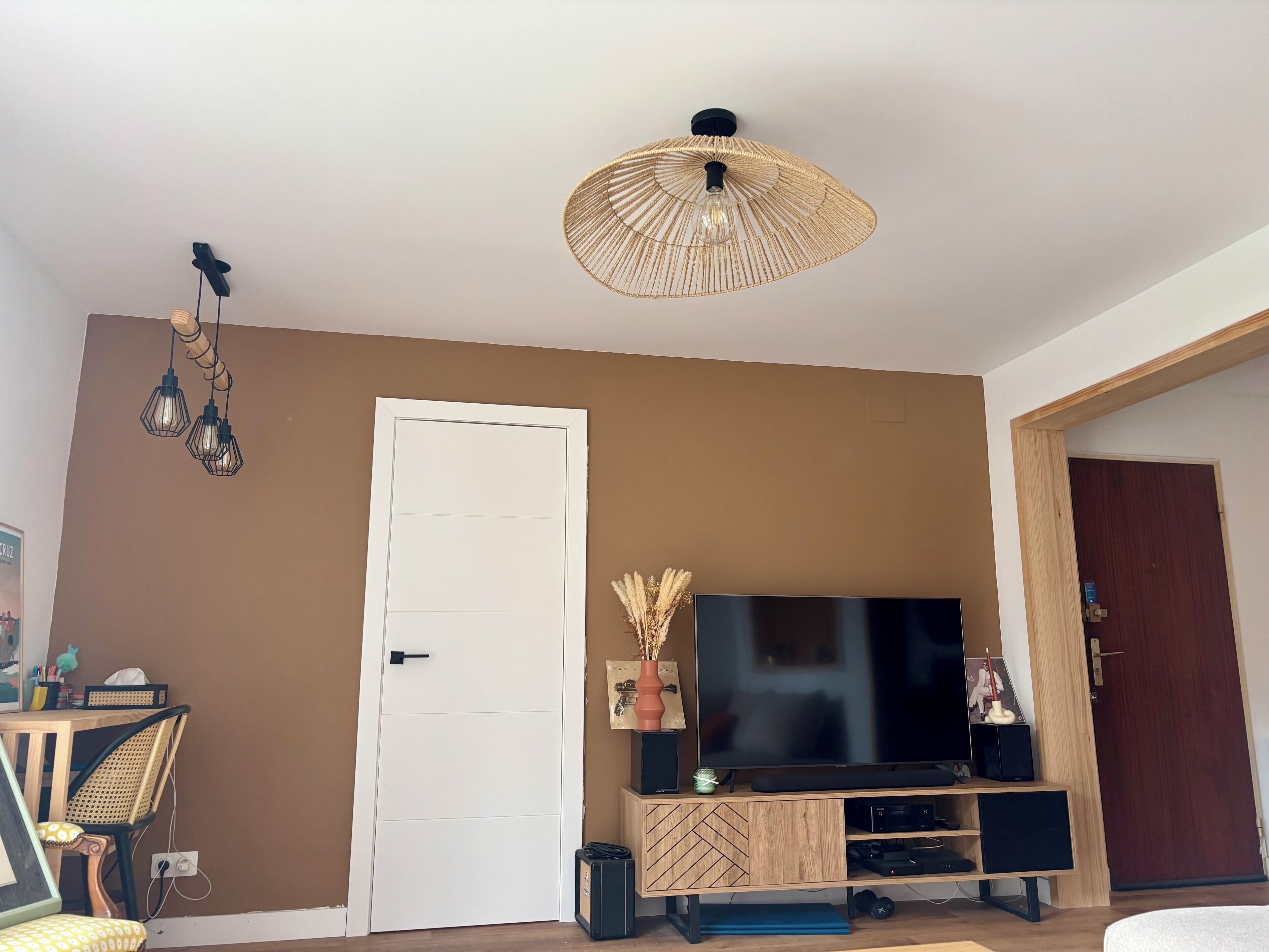 A living room with a television, wooden entertainment unit, and a ceiling light fixture.