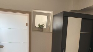 A room with a wardrobe, a small potted plant, and a window with a view. - Vacation apartment Pingo 1 (Ahrbrück)