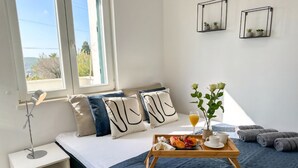 Un dormitorio ordenado con cama, mesita de noche y una bandeja con productos para el desayuno.