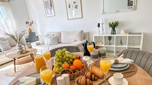 Un desayuno preparado para dos personas, con cruasanes, fruta y zumo de naranja.
