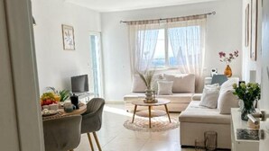 Una sala de estar moderna con un sofá, una mesa de comedor con sillas y un televisor.