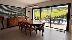 Une cuisine moderne avec un coin repas, de grandes fenêtres et une vue sur un paysage verdoyant.