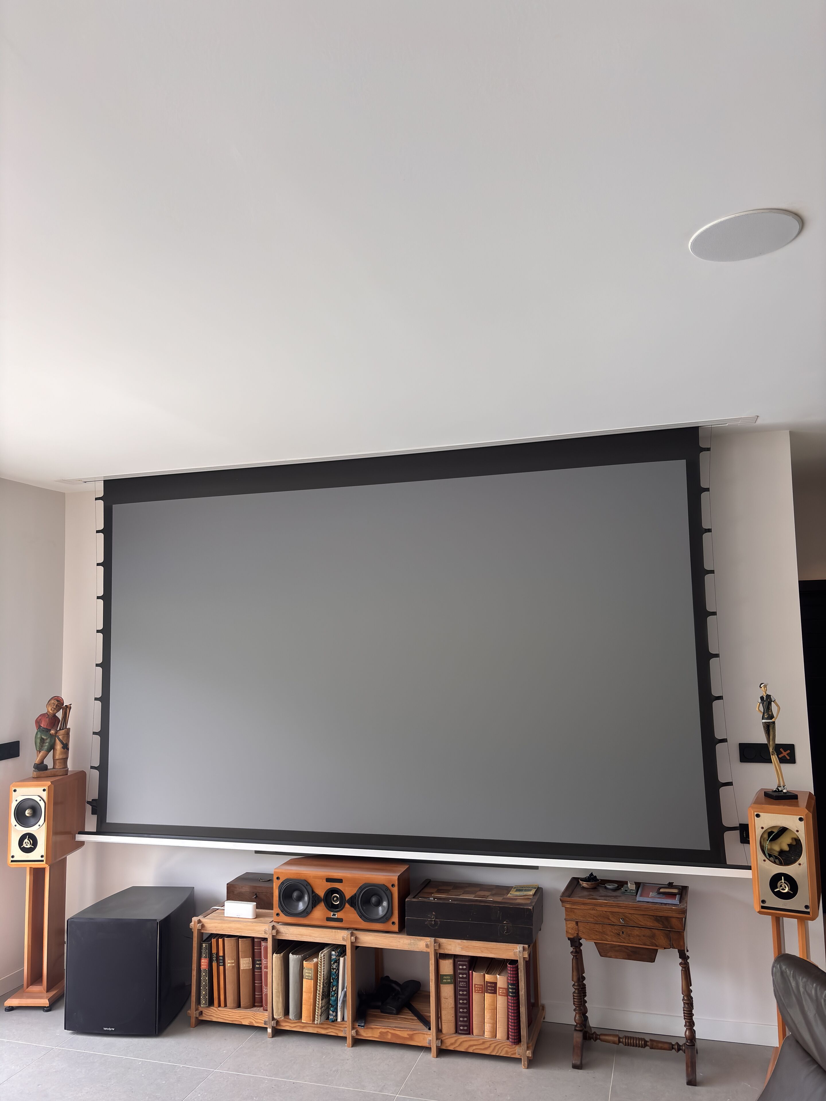 A living room with a large flat-screen TV, wooden bookshelves, a vintage radio, and a small statue.