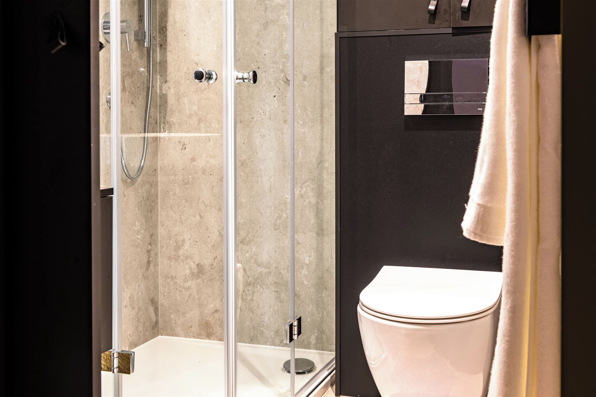 Ein Badezimmer mit einer Duschkabine, einer weißen Toilette und einem Handtuch an einem Haken.