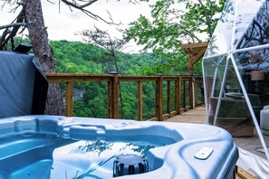 A hot tub on a wooden deck with a view of a forested area.