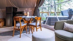 Een gezellige binnenruimte met een eettafel, stoelen, een bank en een koelkast.