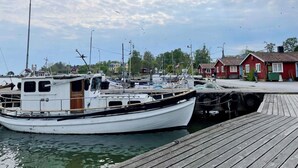 A docked boat at a marina with a wooden pier, surrounded by houses and a clear sky. - 4 Star Holiday Home in Vaddo (Väddö)