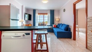 A compact living space with a kitchen, a dining area, and a seating area with a sofa. - Garden city with ocean view&heated pool (Costa Adeje)